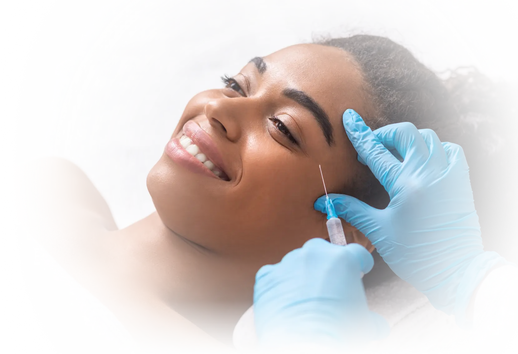 Smiling woman receiving a cosmetic BOTOX® injection in the cheek area, representing minimally-invasive wrinkle reduction in Bellingham at Gallant Lion Medical