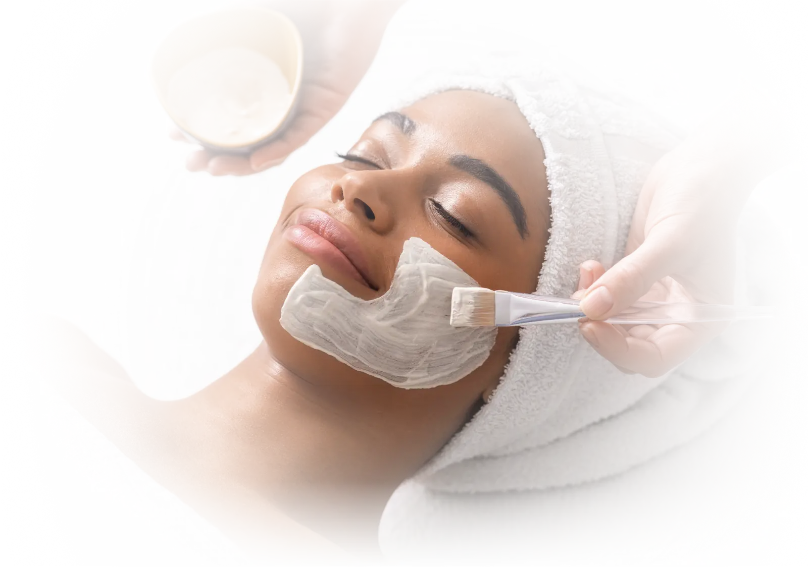Woman receiving a soothing facial treatment with a cream mask, representing holistic aesthetic care and skin rejuvenation services at Gallant Lion Medical