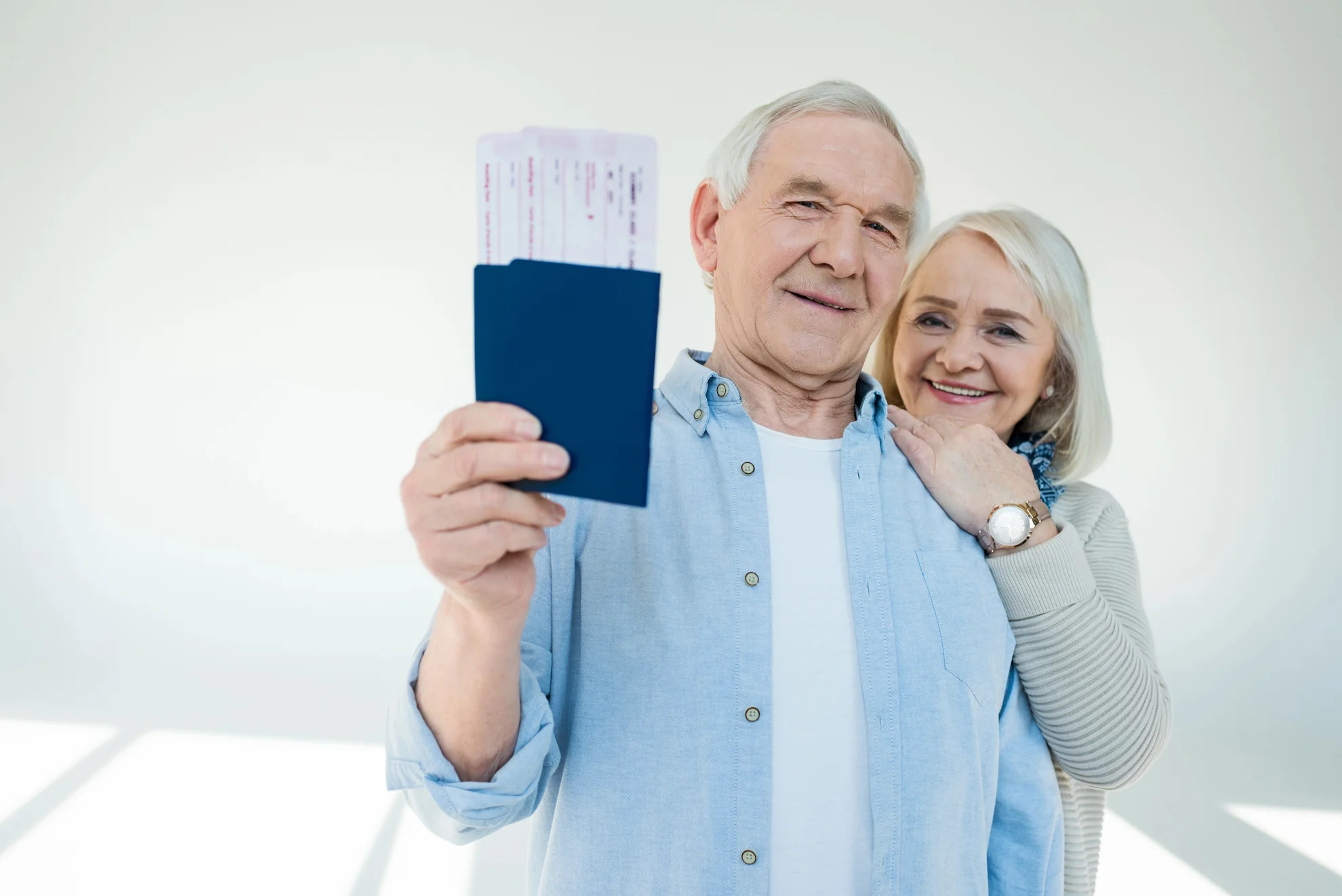 Older couple smiling with passport and boarding passes, representing international patients traveling for regenerative care at Gallant Lion Medical